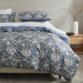 Bed with blue floral duvet and pillows in a bedroom setting.