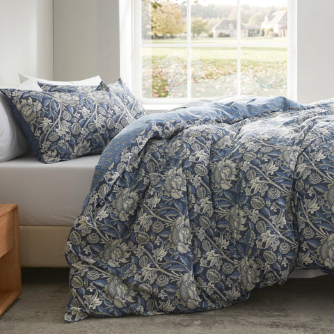 Blue floral patterned comforter on a bed in a room with a window.