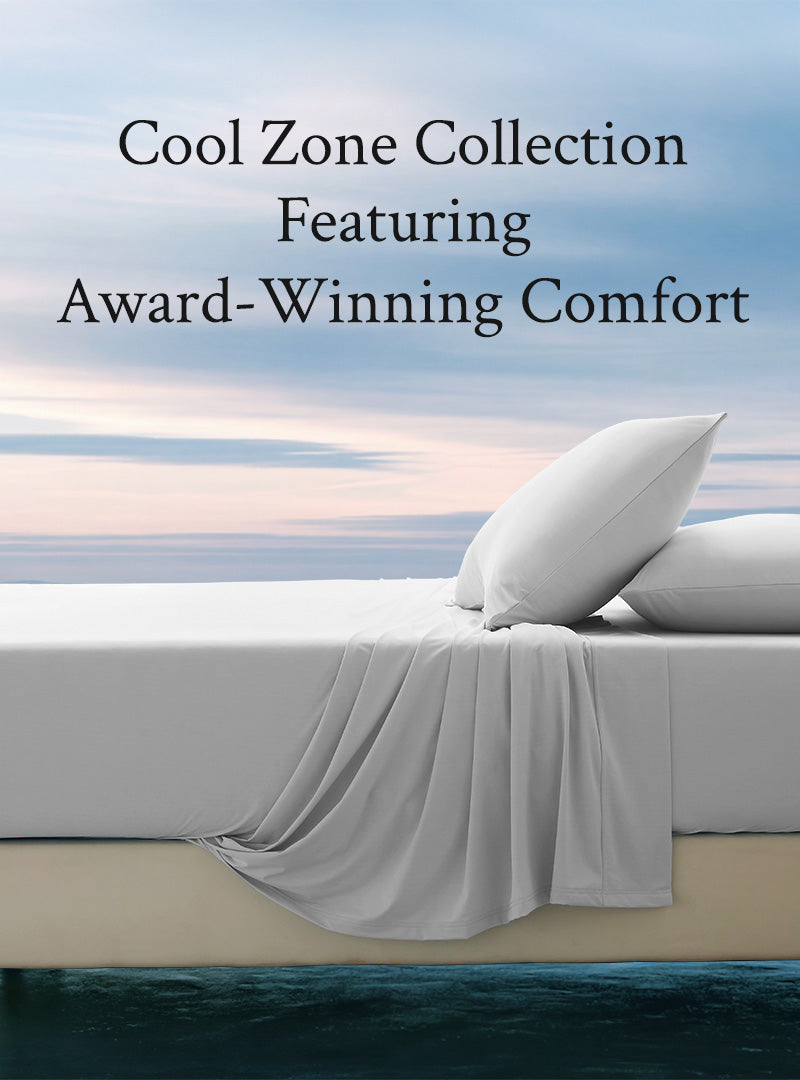 Bed with white pillows and gray bedding against a scenic ocean background, featuring text about the 'Cool Zone Collection'.