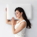 Woman lying on a white cooling pillow against a light gray background