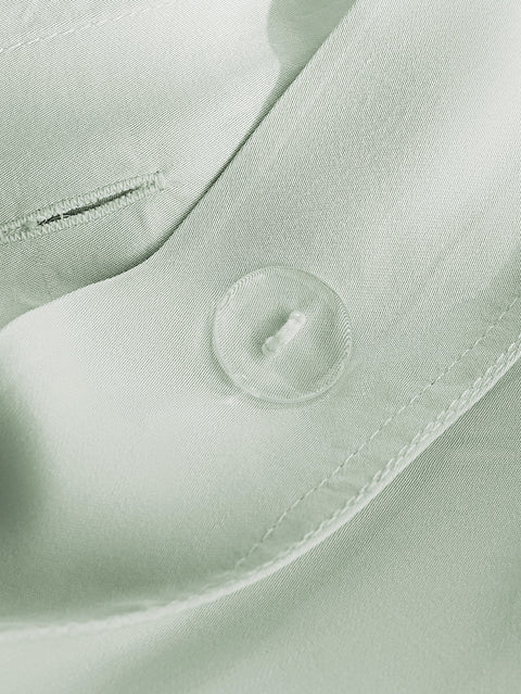 Close-up of a light green fabric with a button and stitching details.