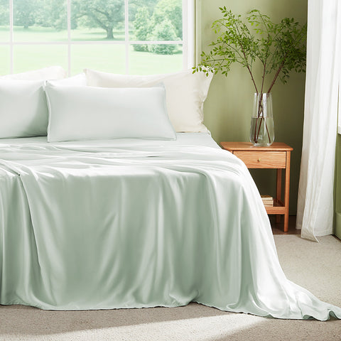 Bed with light green bamboo grove bedding in a bright bedroom with a window and plant.