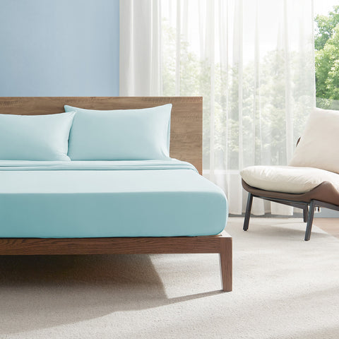 Bed with light blue bedding in a bright bedroom featuring cool zone cooling collection
