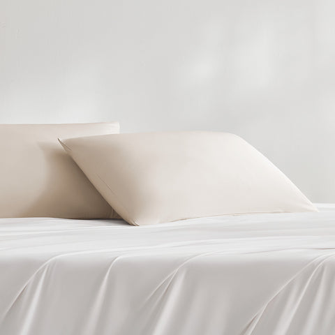 Two teal cooling pillowcases on a white bed sheet
