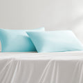 Two blue cooling pillowcases on a white bed sheet