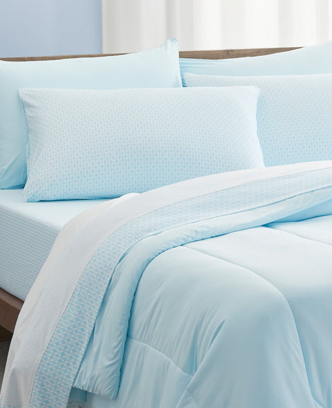 Light blue bedding set on a bed with white curtains in the background