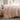 long side view of blush cotton duvet cover set on a bed in a room with a window showing a garden view
