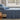long side view of trailing-leaf cotton jersey sheet set on a bed in a room with a window showing a garden view

