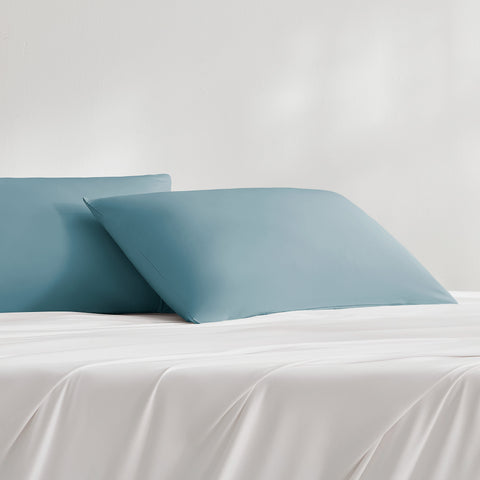 Two teal cooling pillowcases on the white bed sheet