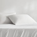 Two white cooling pillows on a white bed sheet
