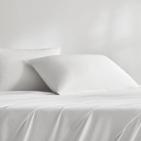 Two white cooling pillows on a white bed sheet
